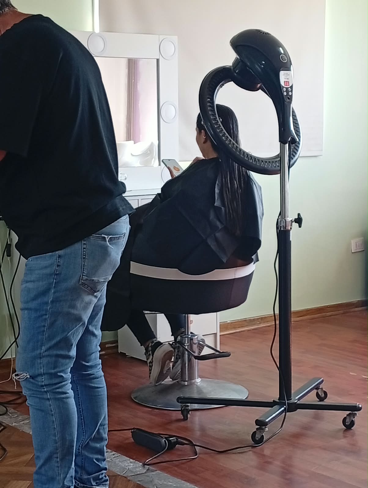 Estilista trabajando junto a una clienta bajo el acelerador de calor