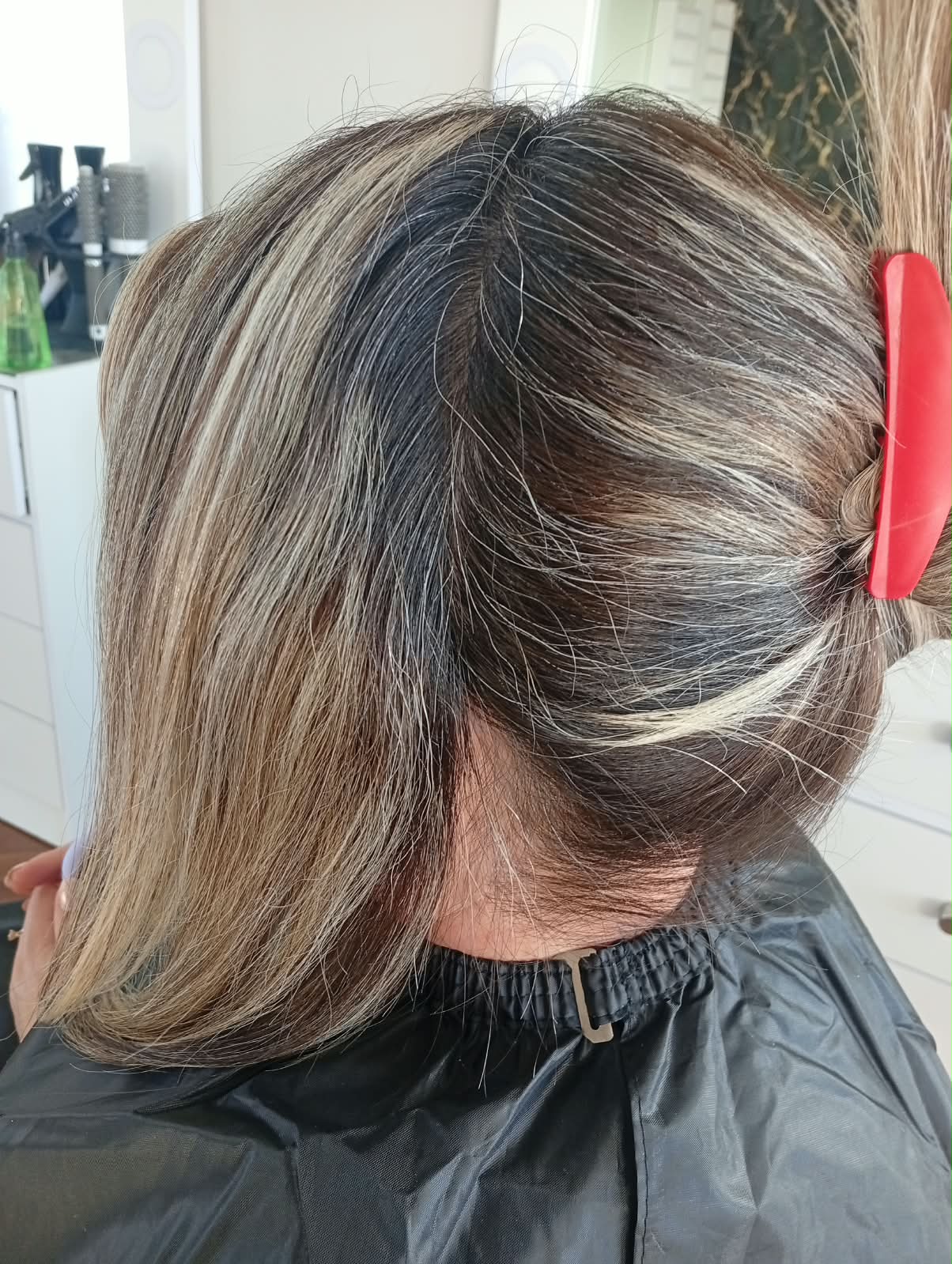 Proceso de reflejos: mechas rubias sobre raíz oscura con pinza roja